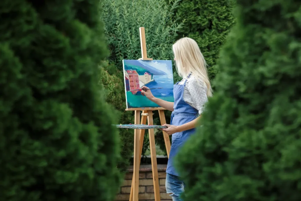 Mulher pintando uma paisagem verde representando o design biofílico